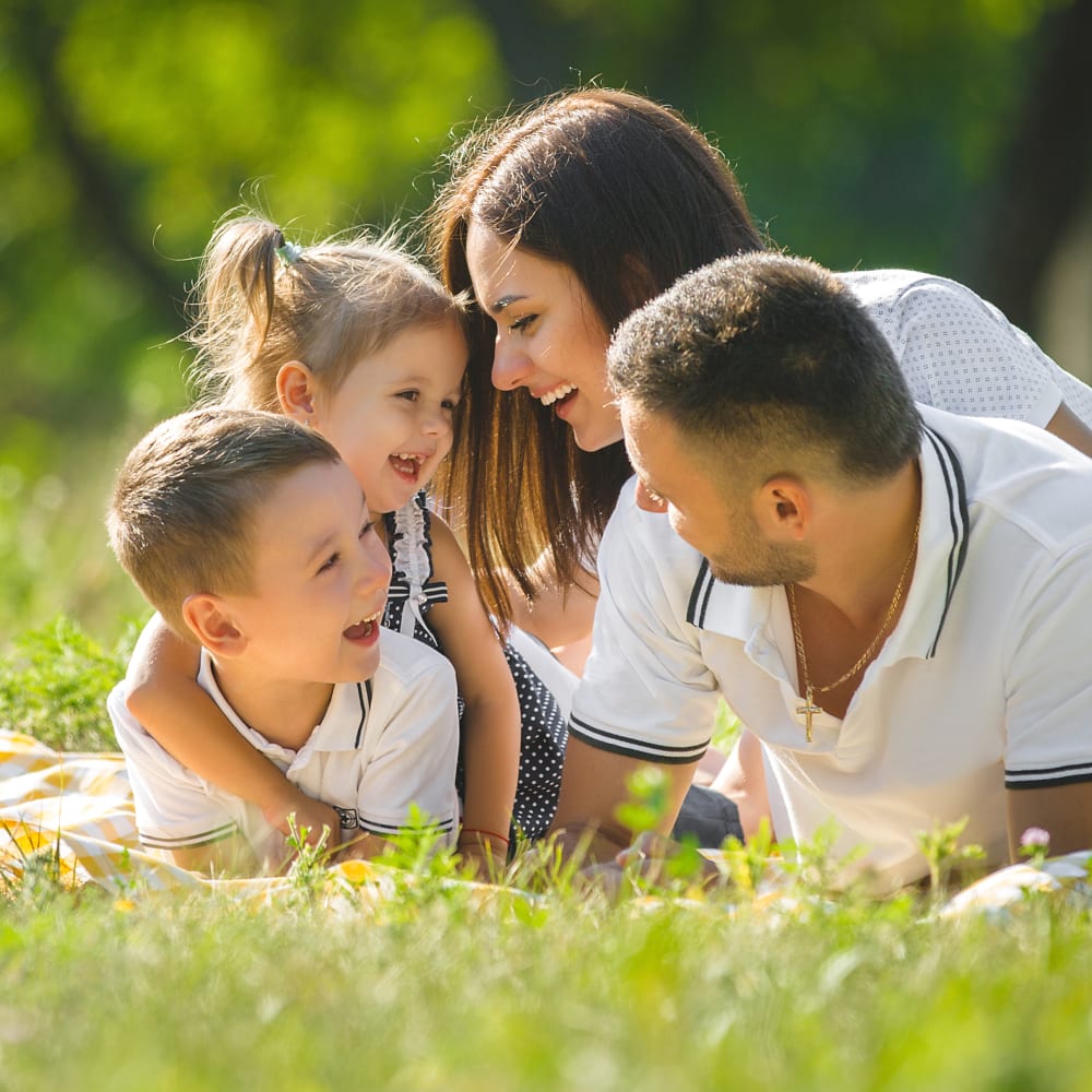 A mother and father are each holding one of their two children and everyone is laughing.