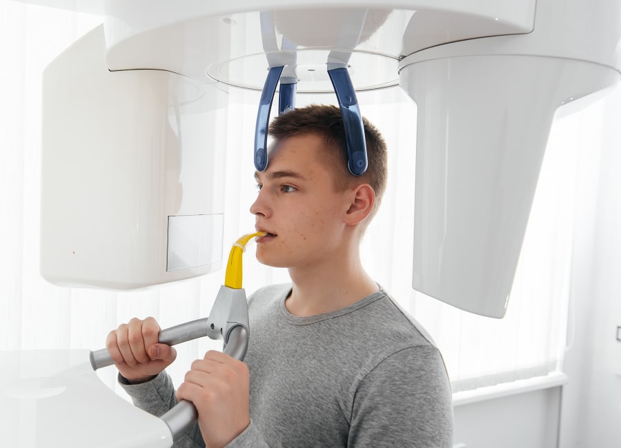 A patient stands with their head in a CBCT machine.